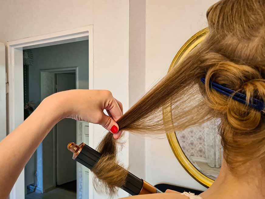 Женщина делает локоны с помощью стайлера Dyson Airwrap. 